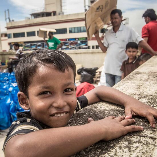 A boy smiles while sitting on the ledge of a building.