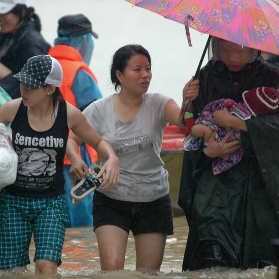 A group of people walking on the beach with an umbrella.