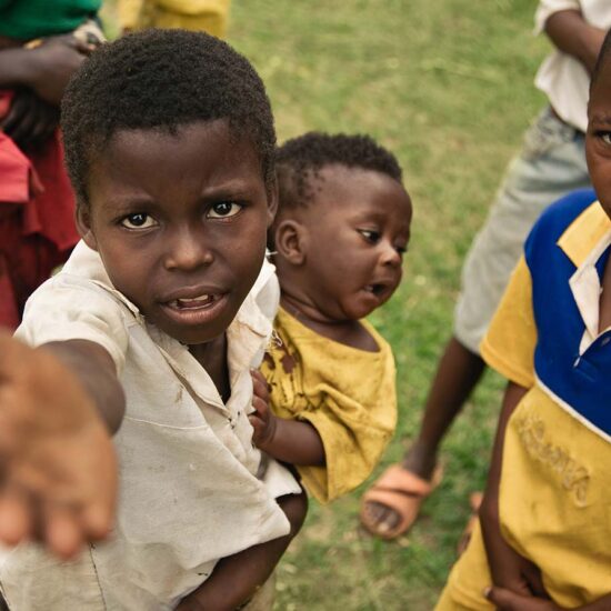 A group of children standing in the grass.