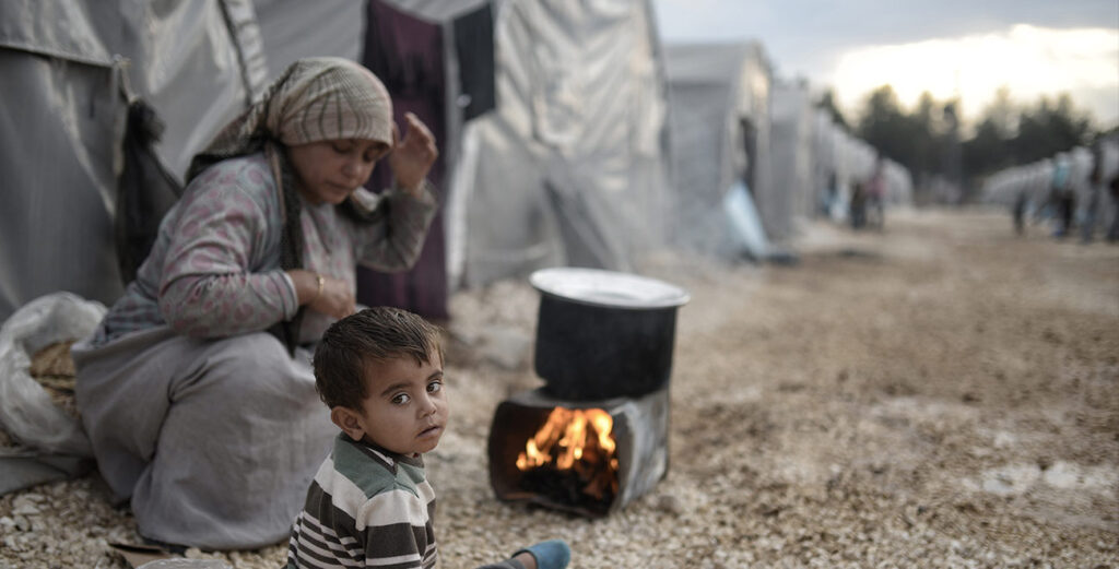 A woman and child in front of an open fire.