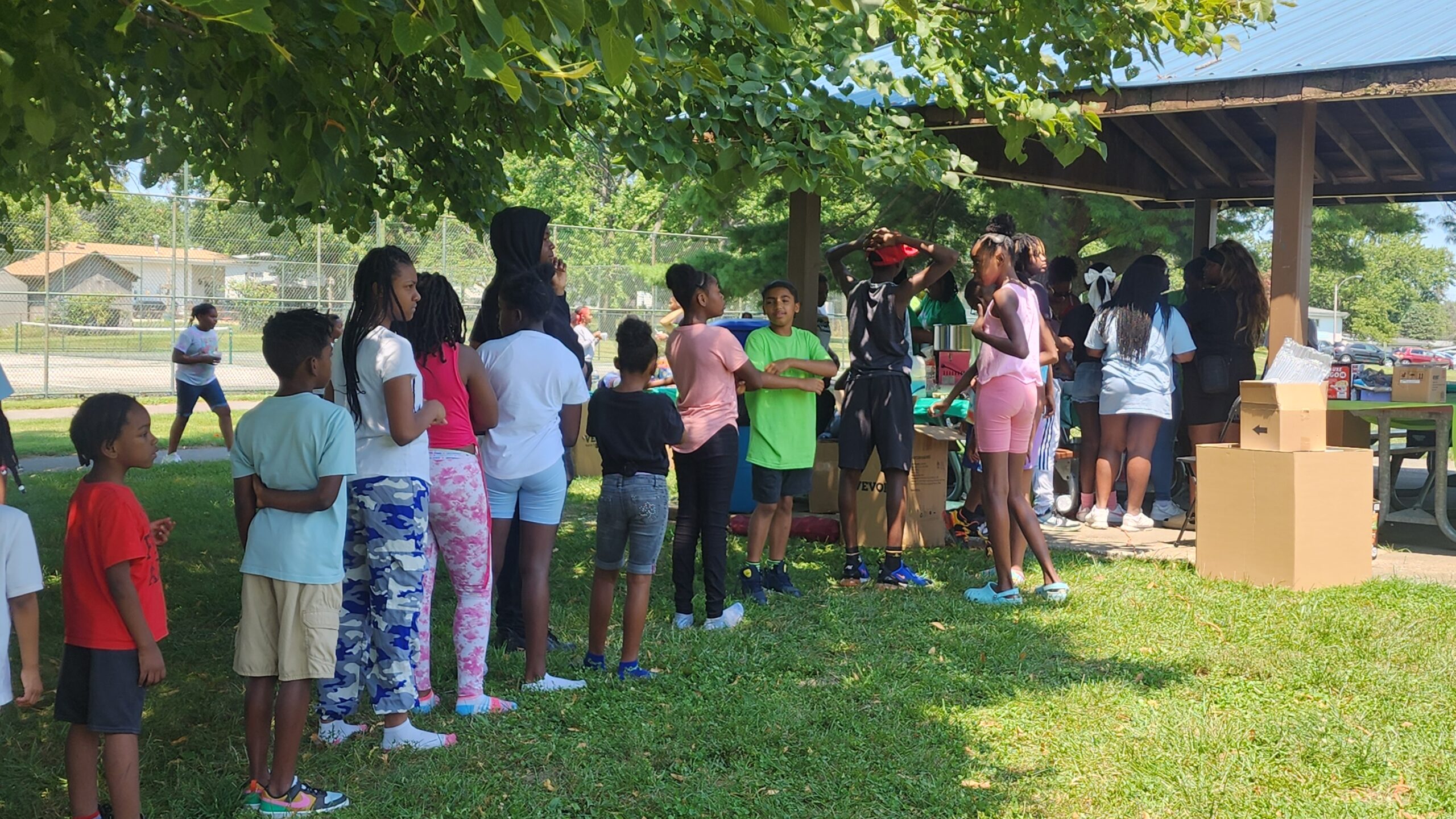 A group of people standing around in the grass.