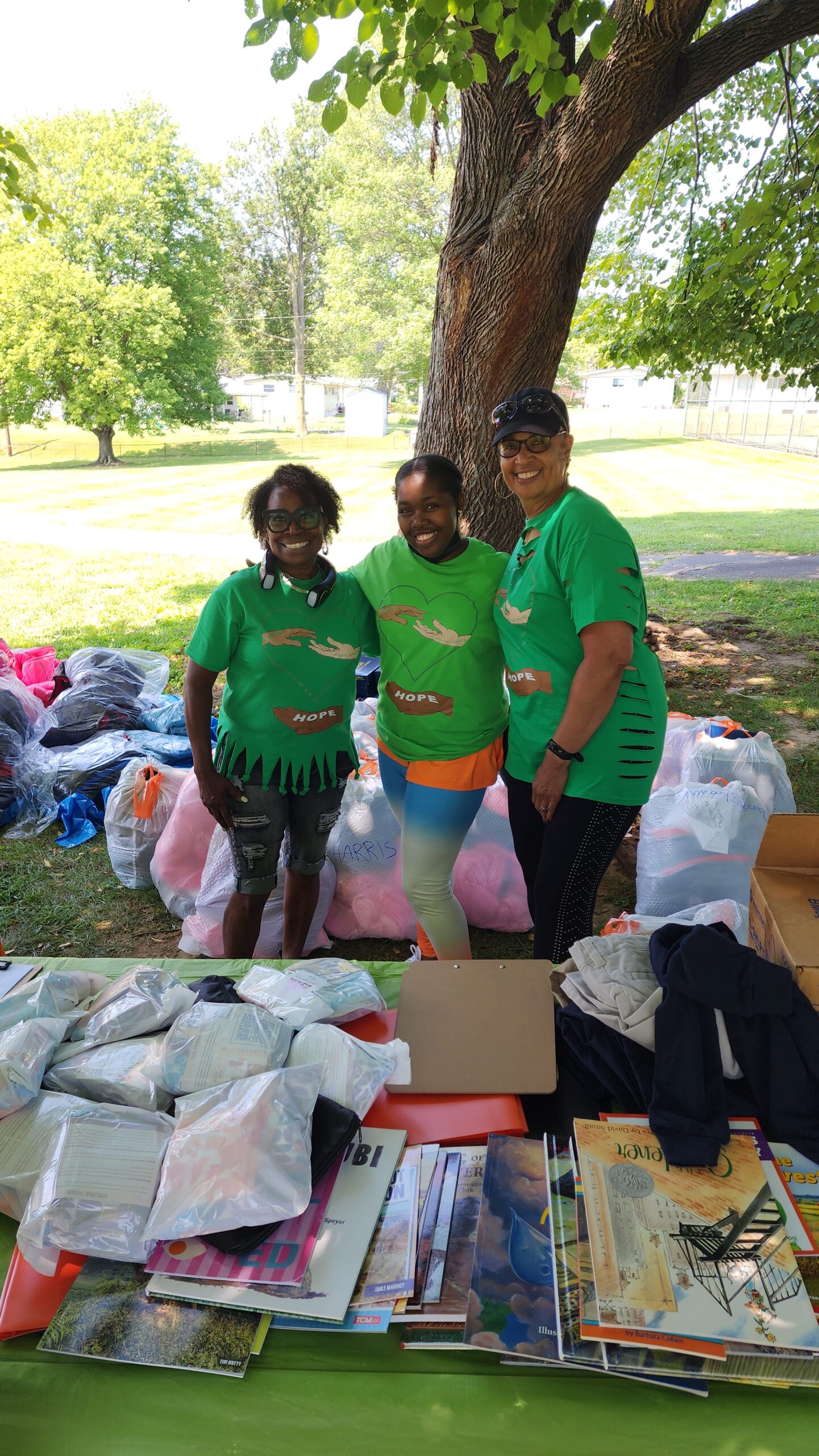 Three people standing in front of a pile of clothes.