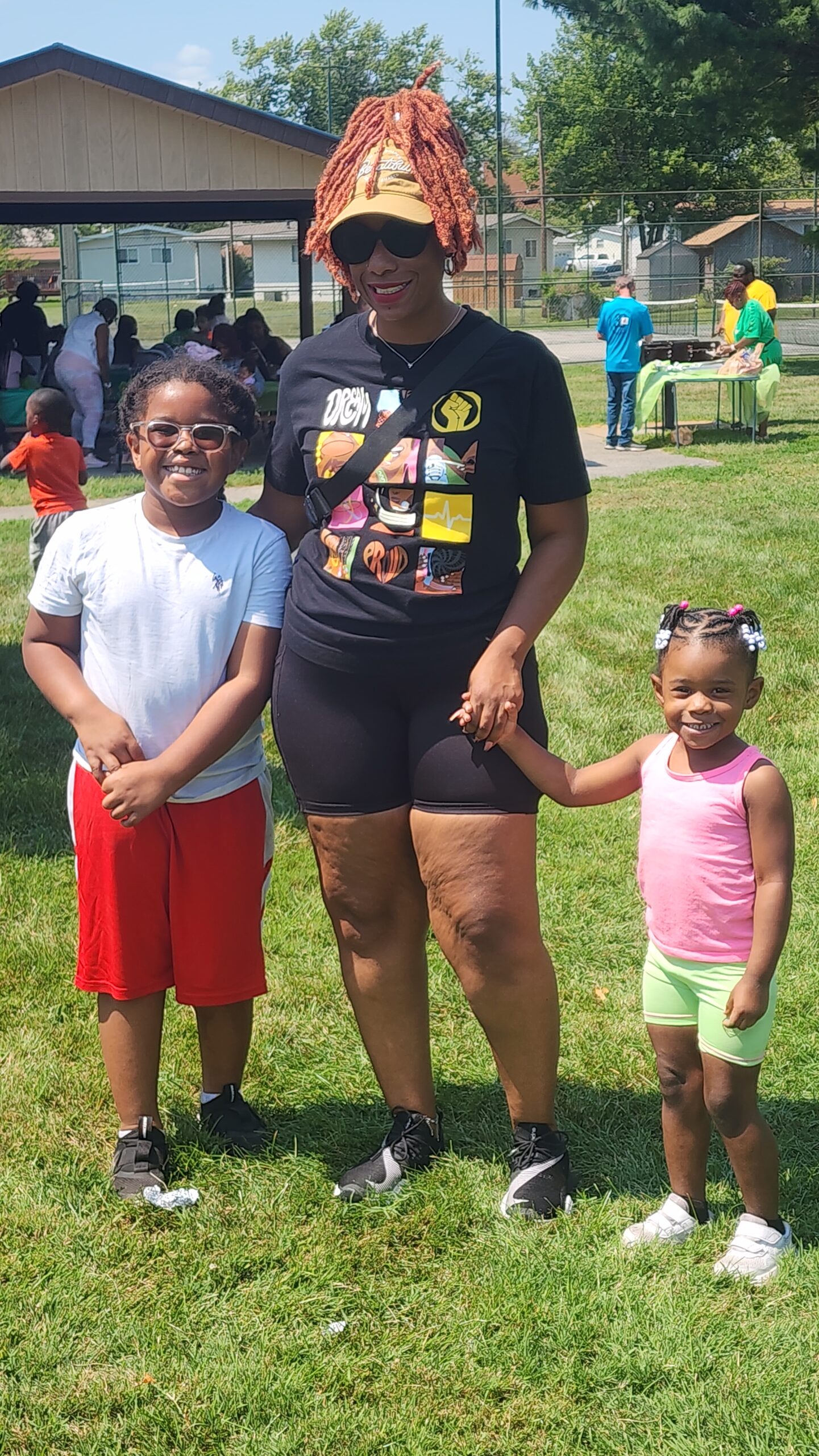 A woman and two children standing in the grass.
