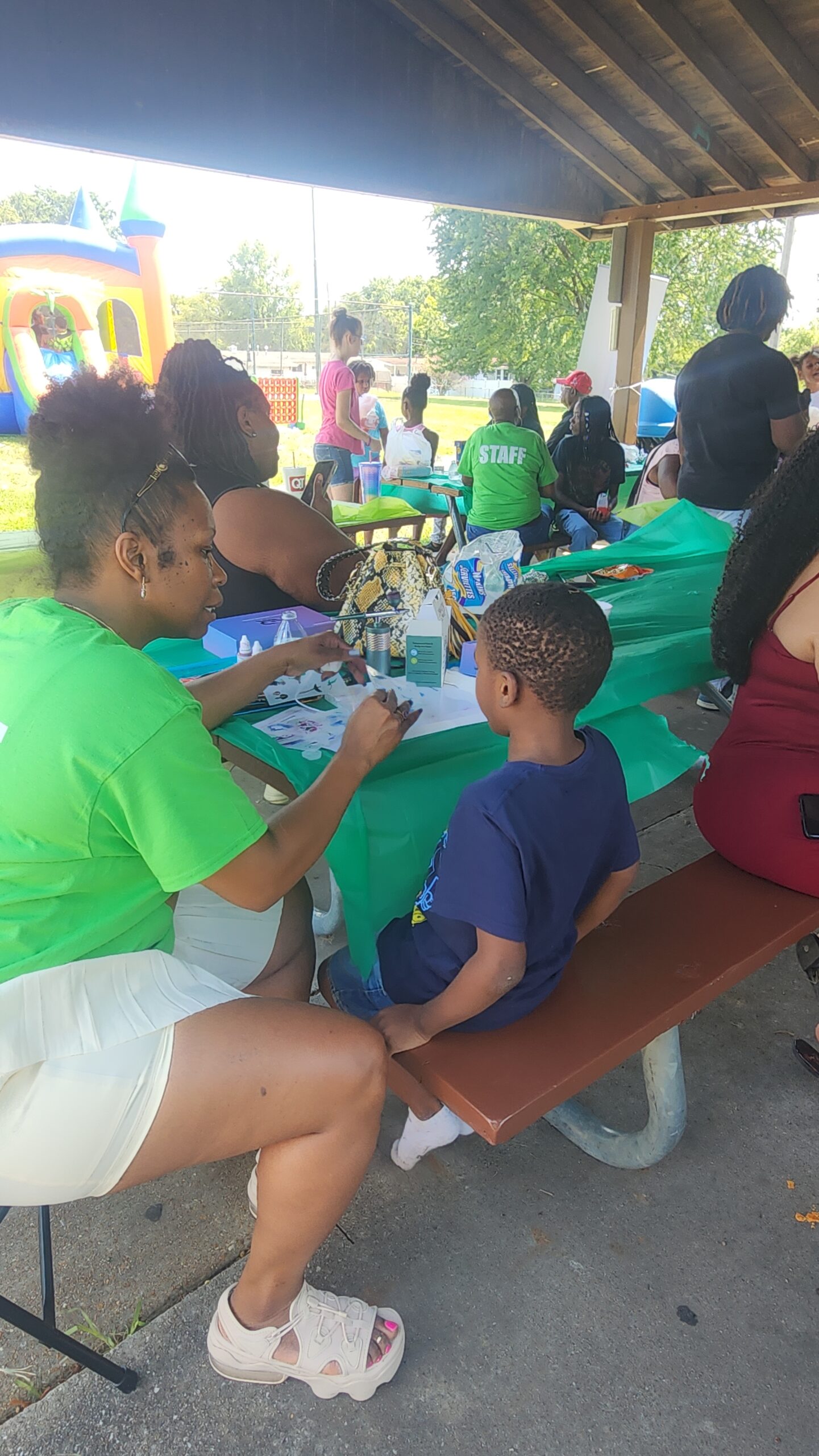 A group of people sitting around tables with green tablecloths.
